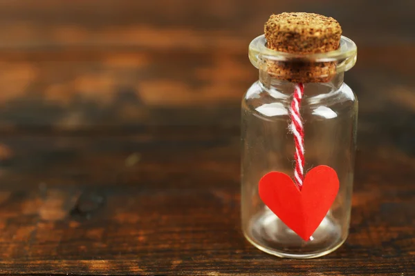 Kleine glazen flesje met hart op rustieke houten tafel achtergrond — Stockfoto