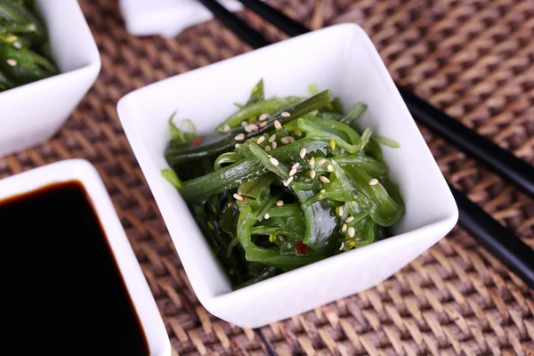 Seaweed salad with say sauce on wicker mat background — Stock Photo, Image