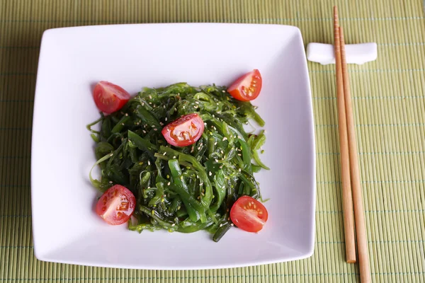 Algensalat mit Scheiben Kirschtomaten auf Bambusmatte Hintergrund — Stockfoto