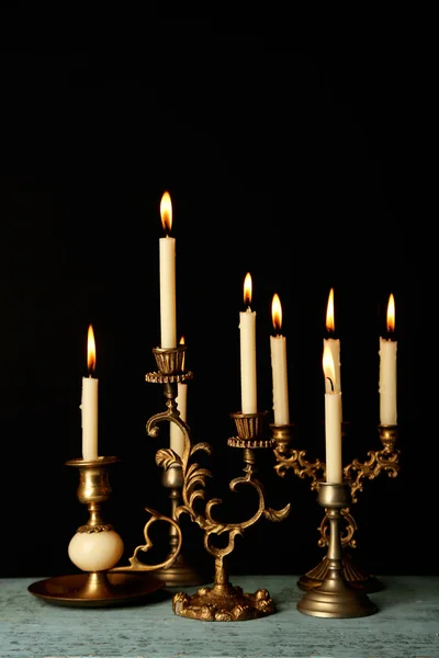 Candelabros retro con velas sobre mesa de madera, sobre fondo negro —  Fotos de Stock