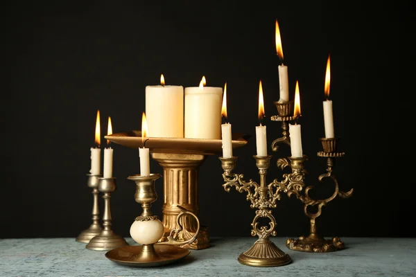 Castiçais retro com velas na mesa de madeira, no fundo preto — Fotografia de Stock