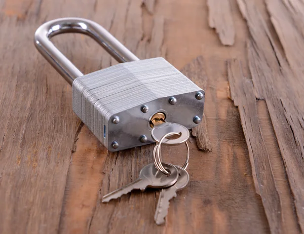 Padlock met toetsen op houten achtergrond — Stockfoto