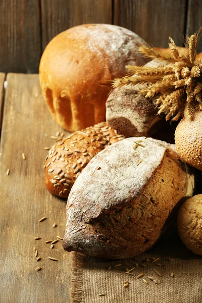 Verschillende brood op tafel op houten achtergrond — Stockfoto