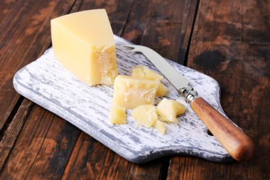 Ahşap masa arka plan üzerinde bıçak ile kesme tahtası üzerinde parmesan peyniri