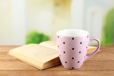 Fincan çay ve masaya parlak arka plan üzerinde kitap