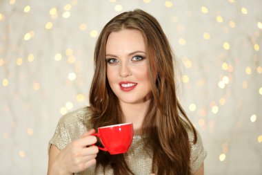 Işıklar arka plan üzerinde sıcak içecek fincan gülümseyen kız