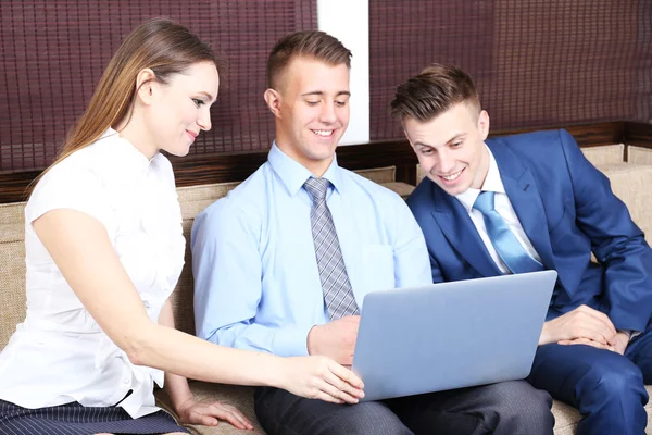 Young business people sitting on couch in office — Stock Photo, Image
