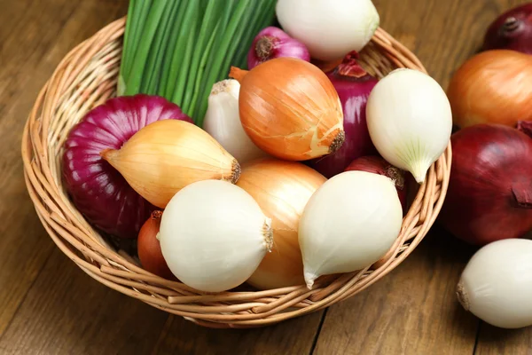 Verschiedene rohe Zwiebeln auf Holzgrund — Stockfoto