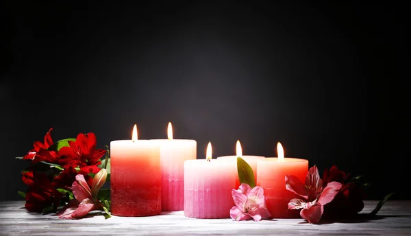 Belas velas com flores na mesa de madeira, no fundo escuro — Fotografia de Stock