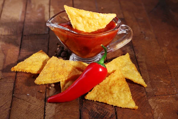 Tasty nachos and bowl with sauce on wooden background — Stock Photo, Image