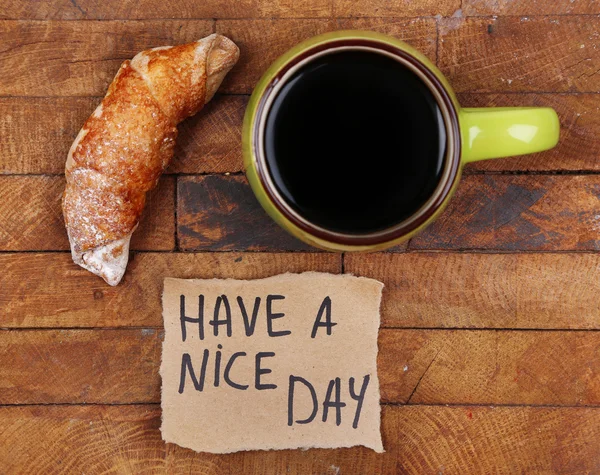 Composizione di caffè, croissant fresco e cartoncino su fondo legno — Foto Stock