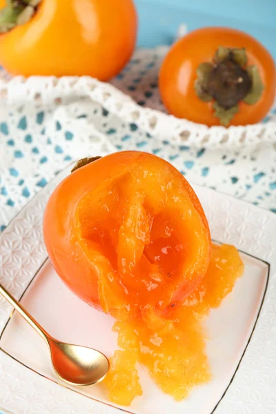 Persimmons mûrs sur assiette, sur fond de bois — Photo