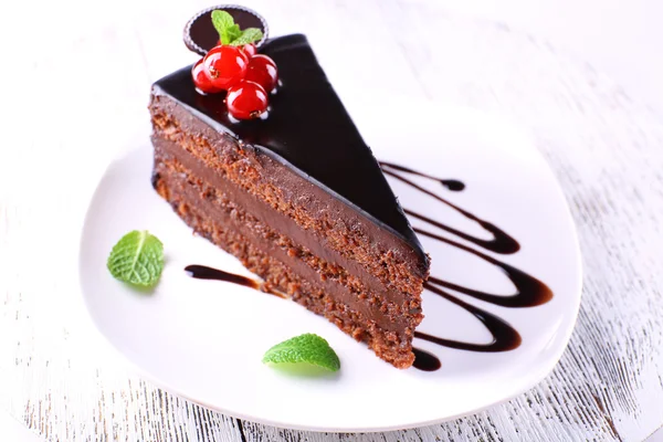 Delicioso bolo de chocolate na placa na mesa no fundo claro — Fotografia de Stock