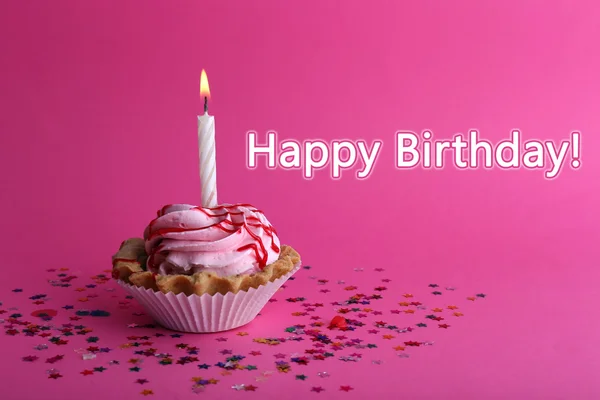 Bolo de xícara de aniversário com vela e estrelas coloridas no fundo rosa — Fotografia de Stock