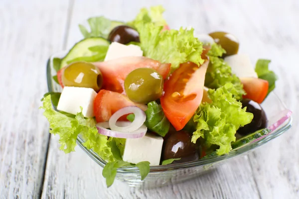 Ensalada griega en plato de vidrio sobre fondo de mesa de madera de color —  Fotos de Stock