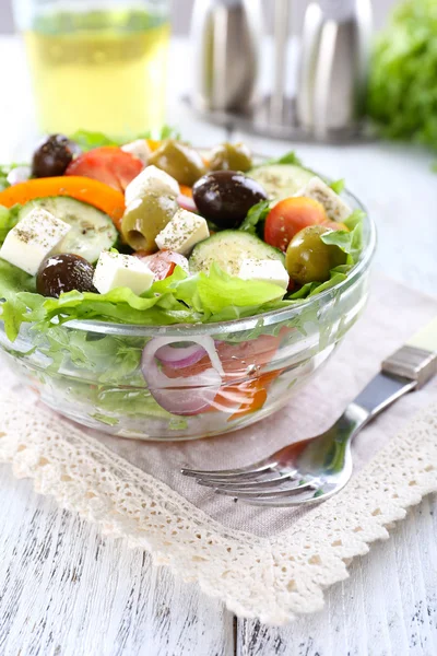 Kreikan salaatti lasi lautasen lautasliina ja väri puinen tausta — kuvapankkivalokuva