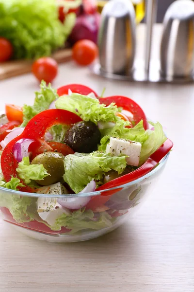 Greek salad in glass dish on wooden table background — Stock Photo, Image