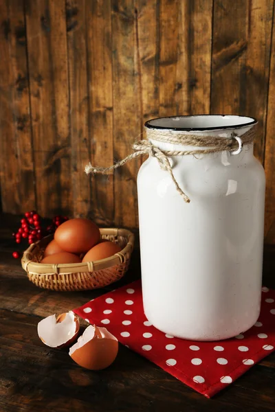 Mjölk kan med ägg och äggskal på rustika trä bakgrund — Stockfoto