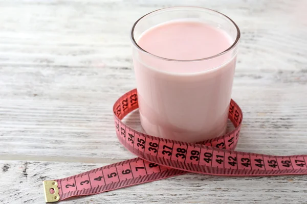 Glass of dietary cocktail with measuring tape on color wooden table background — Stock Photo, Image