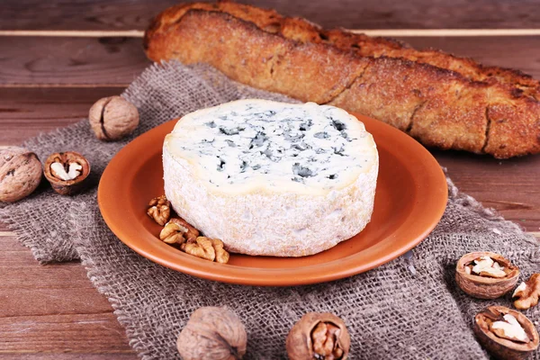 Fromage bleu sur plat en faïence avec noix et baguette sur toile de jute et fond de table en bois — Photo