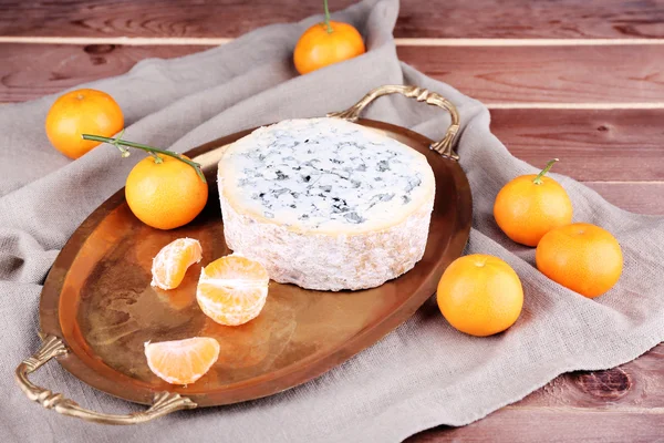 Blue cheese with oranges on metal tray on burlap cloth and wooden table background — Stock Photo, Image