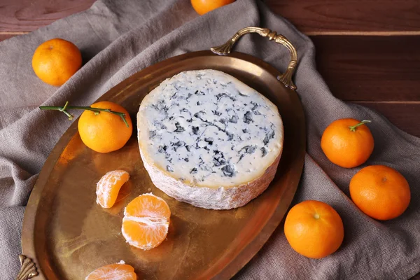 Blue cheese with oranges on metal tray on burlap cloth and wooden table background — Stock Photo, Image