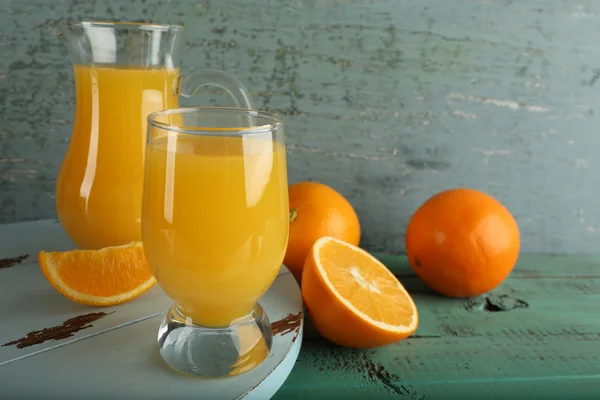 Glas Orangensaft mit Scheiben auf farbigem Holzhintergrund — Stockfoto