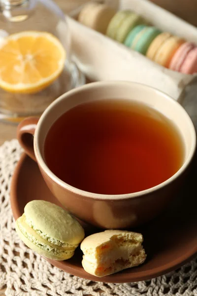 Colorful macaroons with cup of tea on wooden background — Stock Photo, Image