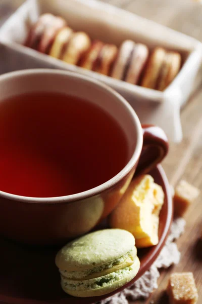 Барвисті макаруни з чашкою чаю на дерев'яному фоні — стокове фото
