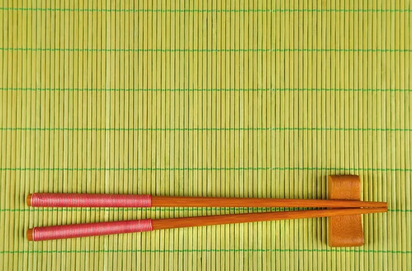 Пара палочек для еды на зеленом бамбуковом фоне — стоковое фото