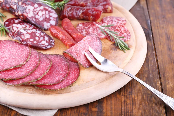 Wurstsortiment auf Schneidebrett mit Klebetuch und hölzernem Tischhintergrund — Stockfoto