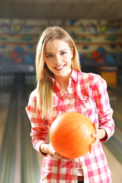 Jeune femme tenant une boule de bowling en club — Photo