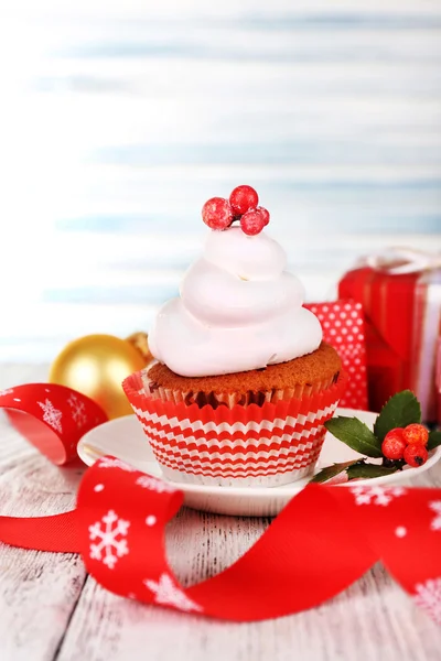 Cup-cake on saucer with Christmas decoration on color wooden table light background — Stock Photo, Image