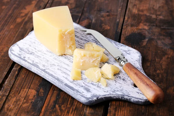 Parmezán sajt vágódeszka, fából készült asztal háttér késsel — Stock Fotó
