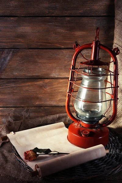 Kerosene lamp with dried rose and letter on wicker mat and wooden planks background — Stock Photo, Image