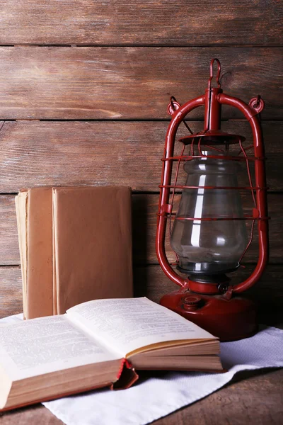Lámpara de queroseno con libros sobre fondo rústico de madera — Foto de Stock