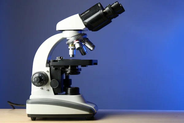 Microscópio na mesa, no fundo da cor — Fotografia de Stock