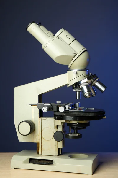 Microscópio na mesa, no fundo da cor — Fotografia de Stock
