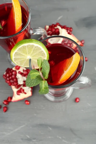 Гранат напиток в стаканах с мятой и ломтиками апельсина и лайма на фоне цвета дерева — стоковое фото