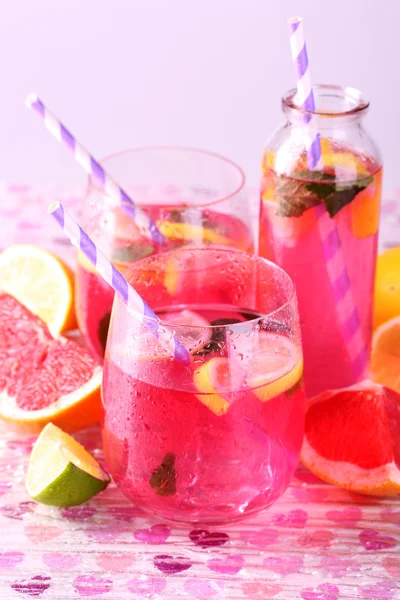 Limonada rosa en vasos y botella sobre fondo brillante — Foto de Stock