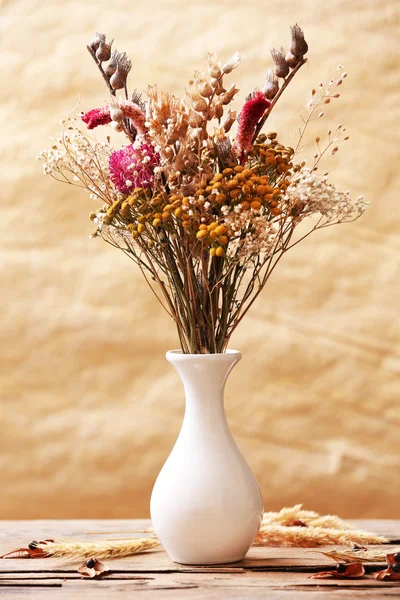 Bouquet of dried flowers in vase on colorful background