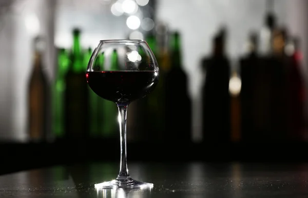 Verre de vin rouge au bar sur fond flou — Photo