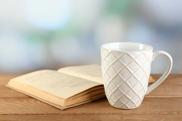 Cup of tea and book on table, on bright background — Stock Photo, Image