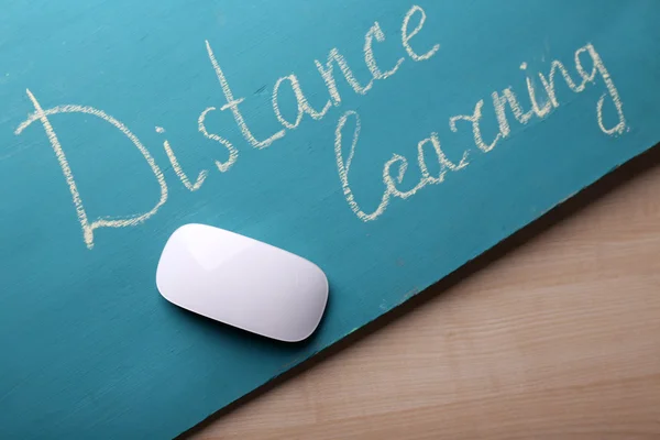 Computermuis en inscriptie afstandsonderwijs op blackboard op houten tafel achtergrond — Stockfoto