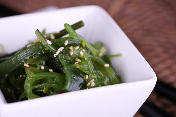 Seaweed salad in bowl on wicker mat background — Stock Photo, Image