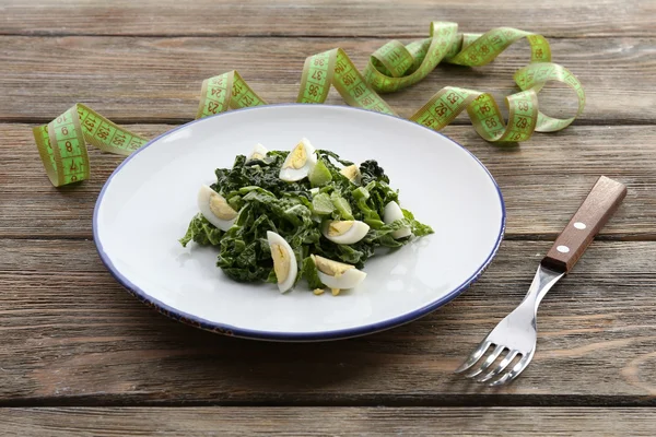 Salad with quail egg and basil in plate with measuring tape on rustic wooden table background — Stock Photo, Image