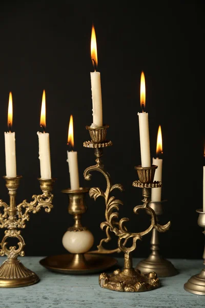 Ретро-подсвечники со свечами на деревянном столе, на черном фоне — стоковое фото