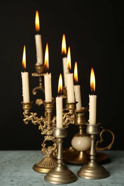 Candelabros retro con velas sobre mesa de madera, sobre fondo negro — Foto de Stock