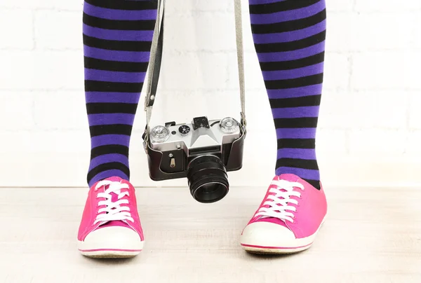 Flicka i sneakers med retro fotokamera i rum — Stockfoto