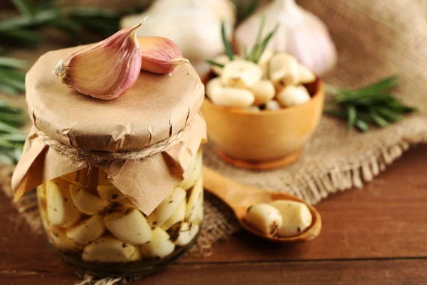 Canned garlic in glass jar on wooden background — Stock Photo, Image